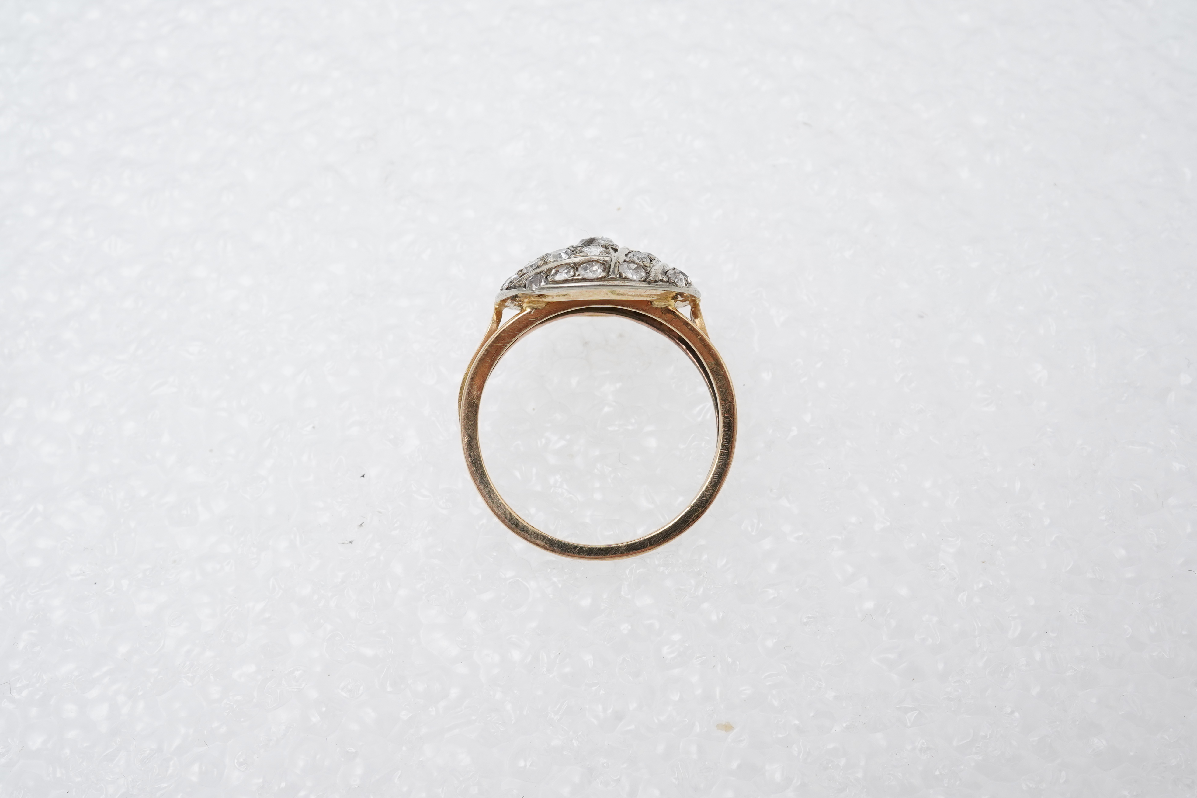 A diamond ring, centring on a circular motif of bombé design, set with geometric arrangements of cushion-shaped, single- and circular-cut diamonds totalling approximately 0.90 carats, to a gold band, size M1/2, indistinc